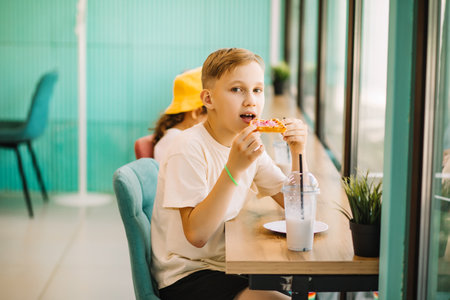 Cute girl and teenager boy eat waffles with ice cream and drinking milkshake in cafe and having fun.の写真素材