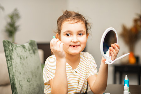 Cute little girl inserting contact lenses into her eye at home. Vision correction and ophthalmology for childrenの写真素材