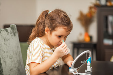 Cute little girl inserting contact lenses into her eye at home. Vision correction and ophthalmology for childrenの写真素材