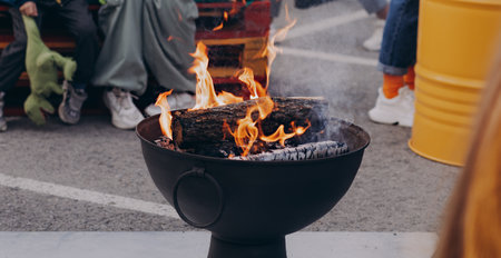 Gathering of people around a striking iron fire pit (fire ring) burning wood.の写真素材
