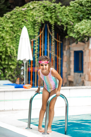 Happy kid little girl playing in outdoor swimming pool at sunny day. Active vacation and healthy lifestyle. Happy summertimeの写真素材