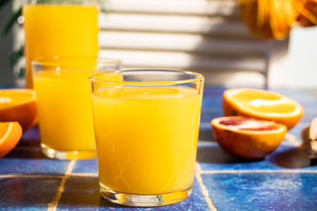 Fresh orange juice on table with slices fruits on blue background.の写真素材