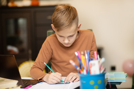 Kid teenager boy pupil at home making homework. Child studying online on laptop. Kid educationの写真素材