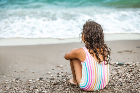 Cute little girl lying on the seashore at the beach in summer. Playful active kid. Holiday vacation with childrenの写真素材
