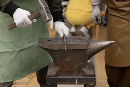 The blacksmith forging the metal on the anvil in smithy.の写真素材