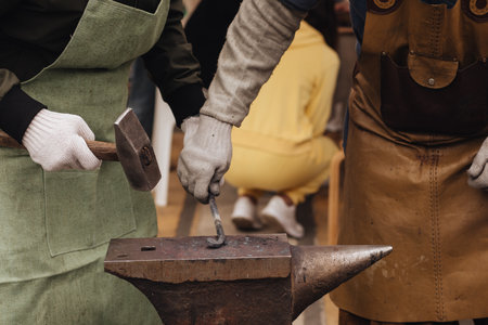 The blacksmith forging the metal on the anvil in smithy.の写真素材