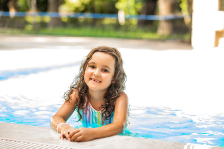 Happy kid little girl playing in outdoor swimming pool at sunny day. Active vacation and healthy lifestyle. Happy summertimeの写真素材