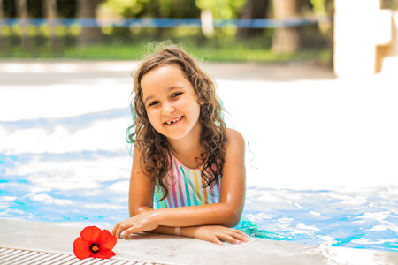 Happy kid little girl playing in outdoor swimming pool at sunny day. Active vacation and healthy lifestyle. Happy summertimeの写真素材