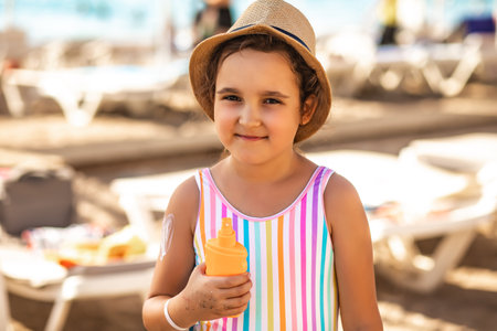 Cute little girl applying sunscreen at the beach in summer. Holiday vacation with childrenの写真素材