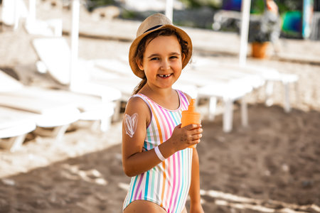 Cute little girl applying sunscreen at the beach in summer. Holiday vacation with childrenの写真素材