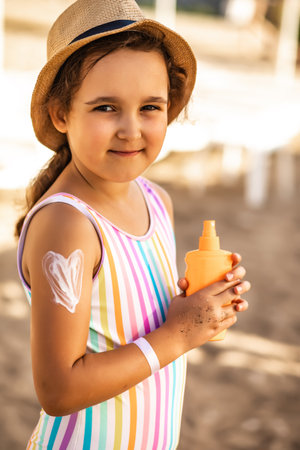 Cute little girl applying sunscreen at the beach in summer. Holiday vacation with childrenの写真素材