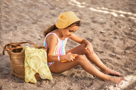 Cute little girl applying sunscreen at the beach in summer. Holiday vacation with childrenの写真素材
