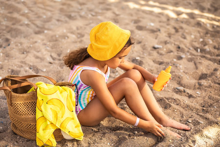 Cute little girl applying sunscreen at the beach in summer. Holiday vacation with childrenの写真素材