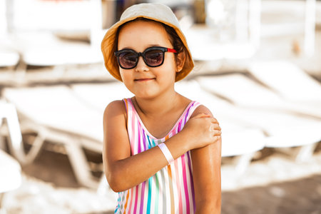 Cute little girl applying sunscreen at the beach in summer. Holiday vacation with childrenの写真素材
