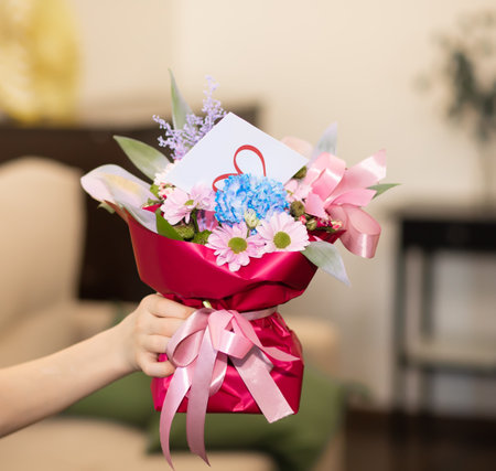 Teenager kid boy child holding bouquet with flowers indoor at home.の写真素材