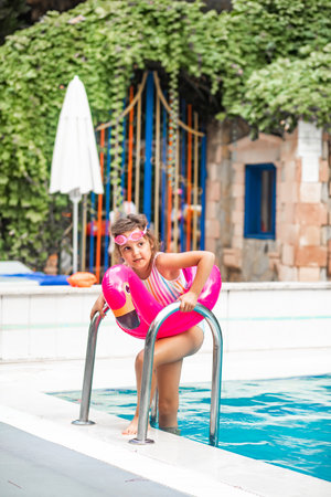 Happy kid little girl playing in outdoor swimming pool at sunny day. Active vacation and healthy lifestyle. Happy summertimeの写真素材