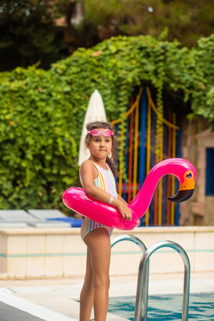 Happy kid little girl playing in outdoor swimming pool at sunny day. Active vacation and healthy lifestyle. Happy summertimeの写真素材