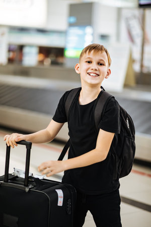 Teenager kid boy at airport with suitcase waiting for boarding to flight. Active family lifestyle travel by air with child on vacation.の写真素材