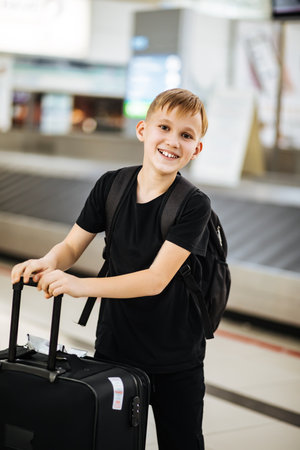 Teenager kid boy at airport with suitcase waiting for boarding to flight. Active family lifestyle travel by air with child on vacation.の写真素材