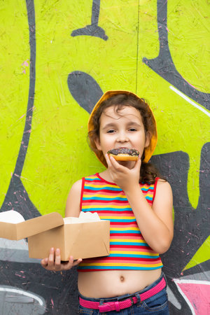 Little cute girl kid eating chocolate sweet and tasty donut. Child snacking on food outdoors.の写真素材