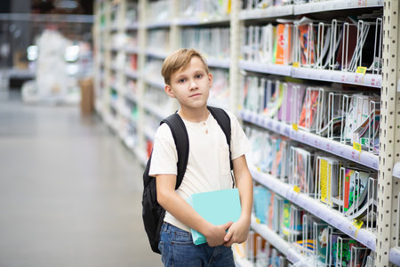 Cute teenager kid boy choosing school stationery in supermarket.の写真素材