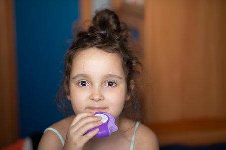 Cute little girl using asthma inhaler at home.の写真素材