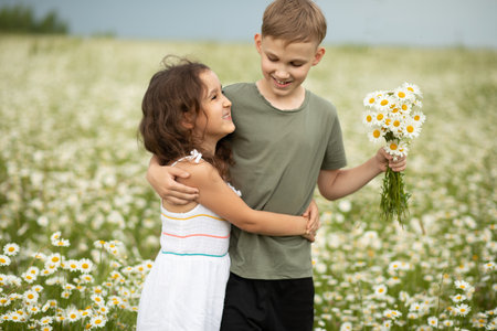 Cute little child girl and teen boy at camomile field picking flowers and having fun. Family vacation. Children outdoor activity.の写真素材