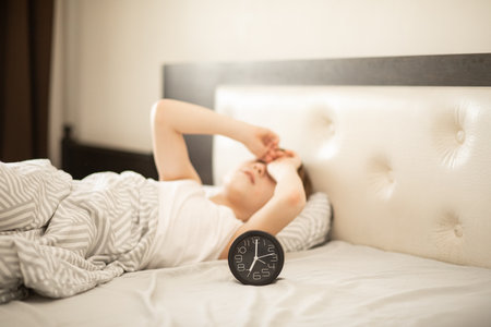 Kid boy teenager waking up morning. Alarm clock nearbyの写真素材