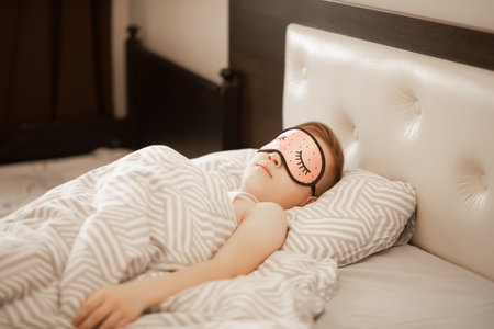 Teenager kid boy in a pink night mask sleeping on bedの写真素材