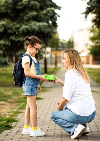 Woman mother and her charming little daughter. Mom leads little school child first day at schoolの写真素材