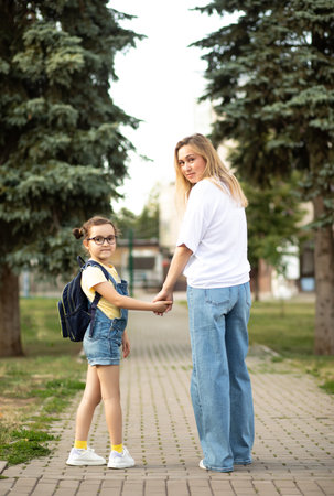 Woman mother and her charming little daughter. Mom leads little school child first day at schoolの写真素材