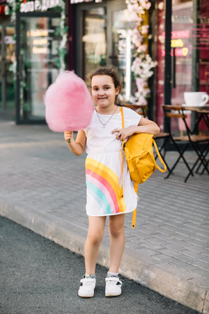Cute little girl eating cotton candy. Happy childhood. Summer holidays conceptの写真素材