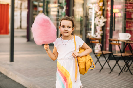 Cute little girl eating cotton candy. Happy childhood. Summer holidays conceptの写真素材