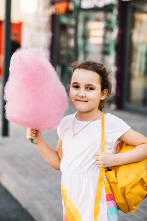 Cute little girl eating cotton candy. Happy childhood. Summer holidays conceptの写真素材