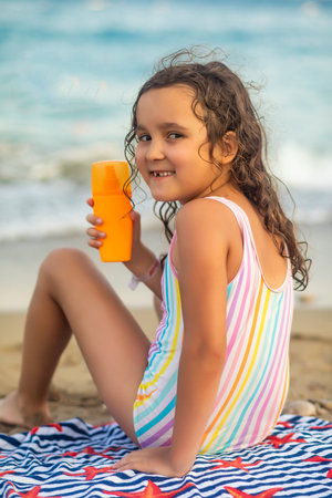 Cute little girl applying sunscreen at the beach in summer. Holiday vacation with childrenの写真素材