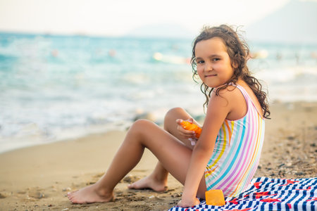 Cute little girl applying sunscreen at the beach in summer. Holiday vacation with childrenの写真素材