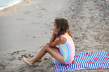 Cute little girl sitting on the seashore at the beach in summer. Playful active kid. Holiday vacation with childrenの写真素材