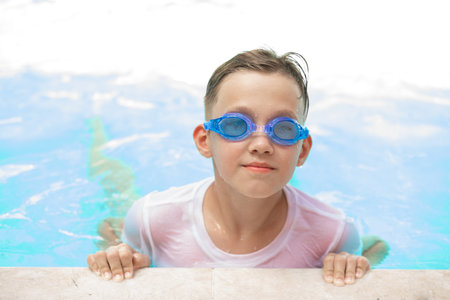 Happy kid boy playing in outdoor swimming pool at sunny day. Active vacation and healthy lifestyle. Happy summertimeの写真素材