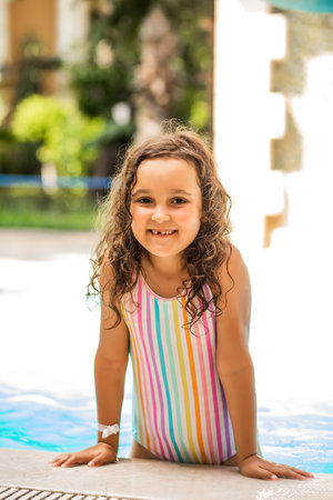 Happy kid little girl playing in outdoor swimming pool at sunny day. Active vacation and healthy lifestyle. Happy summertimeの写真素材
