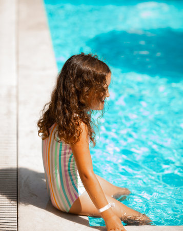 Happy kid little girl playing in outdoor swimming pool at sunny day. Active vacation and healthy lifestyle. Happy summertimeの写真素材
