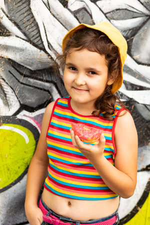 Little cute girl kid eating chocolate sweet and tasty donut. Child snacking on food outdoors.の写真素材