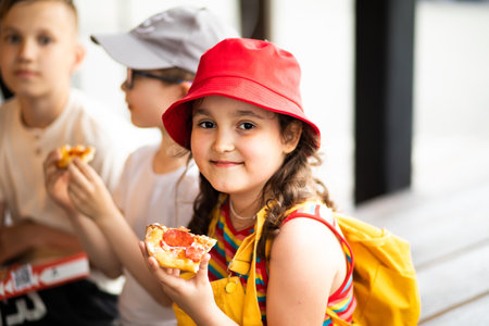 Kids eating pizza. Children snacking on food outdoors.の写真素材