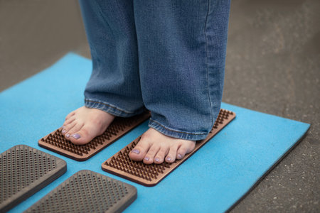Woman stands with bare feet on nails on a sadhu board while practicing meditation. The practice of...