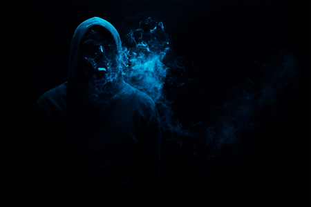 Man in black hood in the night darkness, dimly lit, concepts of danger, crime terrorの写真素材