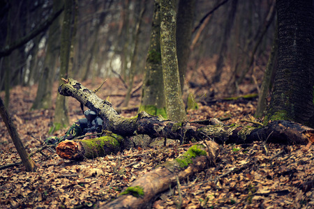 Paintball player in protective uniform and mask aiming gun in the forrest coverの写真素材