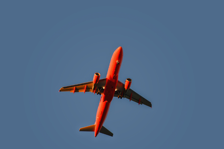 Red airplane in the sky at sunset with landing lightsのeditorial素材