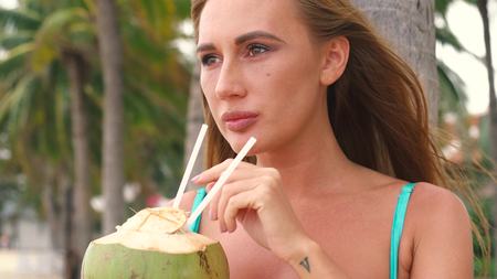 Portrait of sexy bikini young woman drinking coconut near palm trees. vietnam.