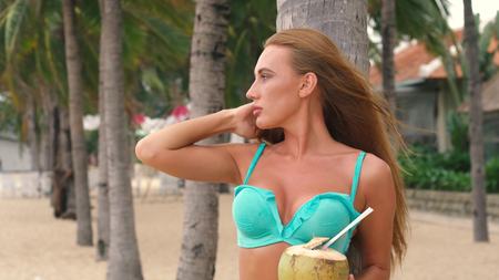 Portrait of sexy bikini young woman with green coconut on the beach. vietnam.の写真素材
