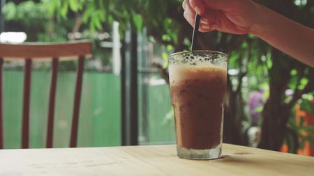 girl stirs iced coffee and takes itの写真素材