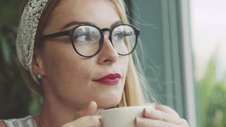 Emotional woman drinking coffee in cafe. Female student joking and laughing.の写真素材